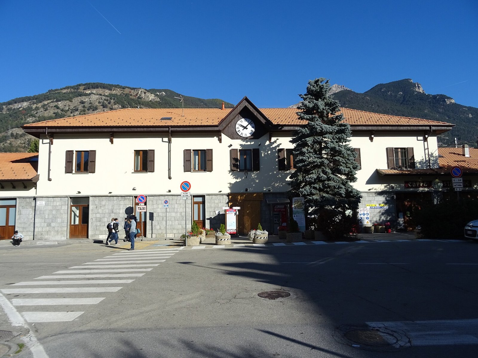 Facciata della stazione ferroviaria di Oulx-Cesana-Claviere-Sestriere con l'orologio e le montagne della Val Susa