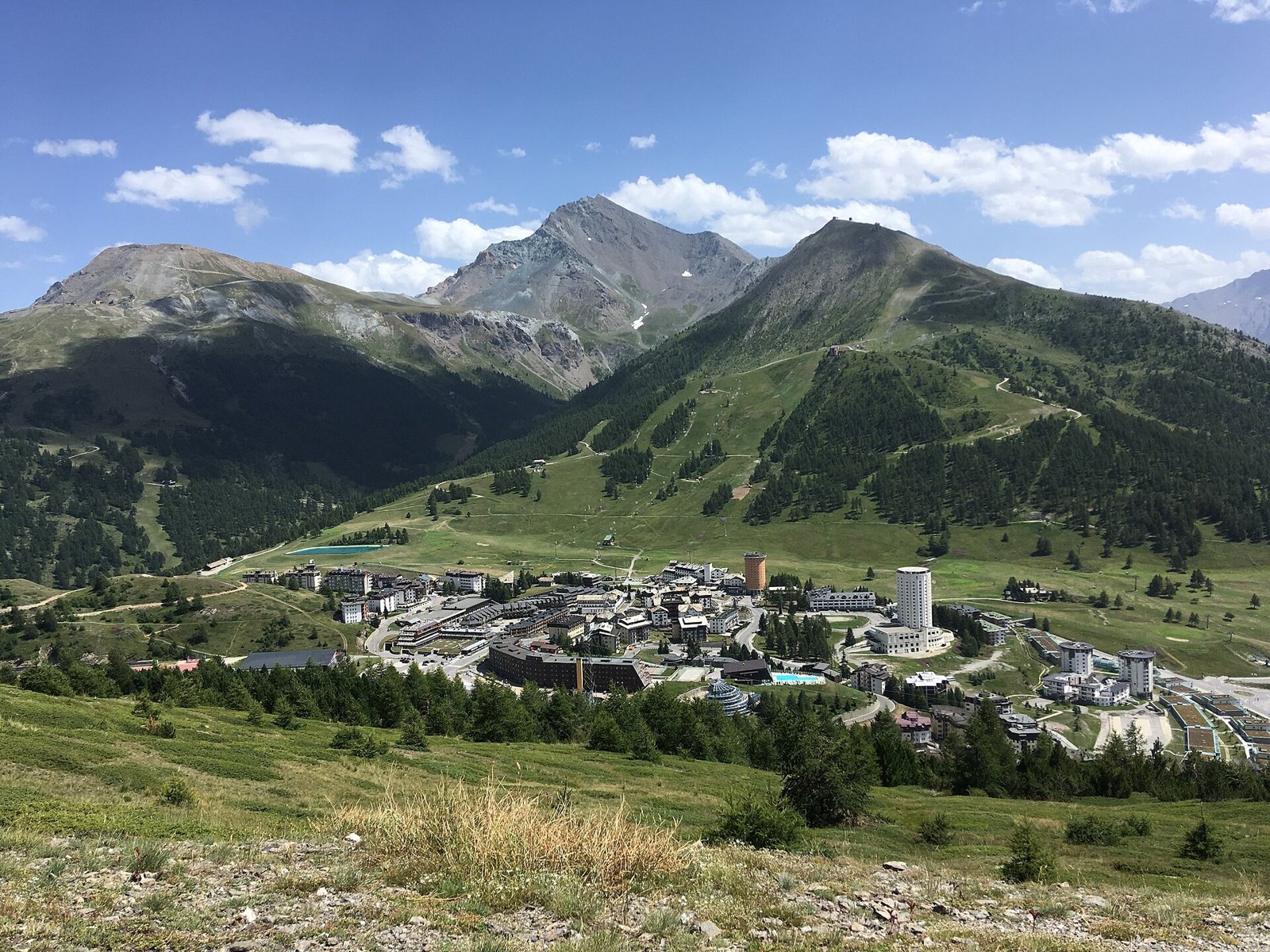 Veduta estiva di Sestriere con le torri, i prati verdi e le montagne intorno al colle