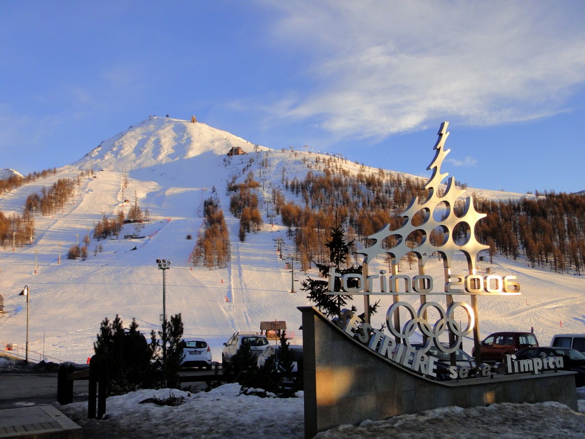 Il monumento dedicato ai Giochi di Torino 2006 a Sestriere, con le piste innevate e i larici sullo sfondo al tramonto